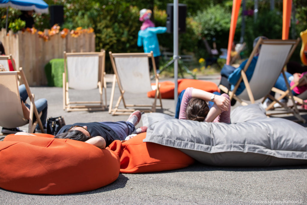 Personnes faisant la sieste pendant le spectacle Pour La Sieste sur des coussins
